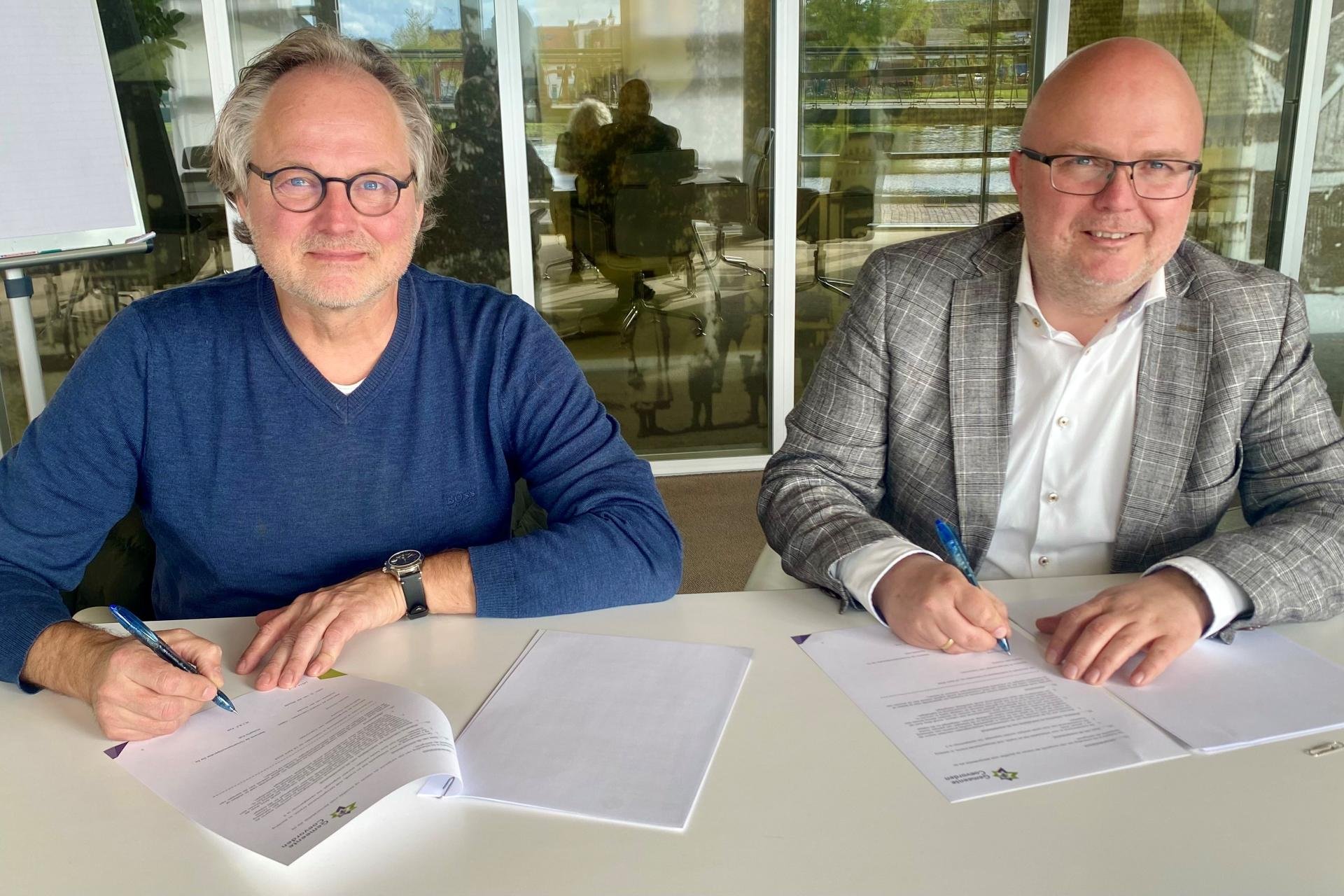 Martin Kok van Huisartsencoöperatie De Es en wethouder Jeroen Huizing ondertekenen de samenwerkingsovereenkomst..