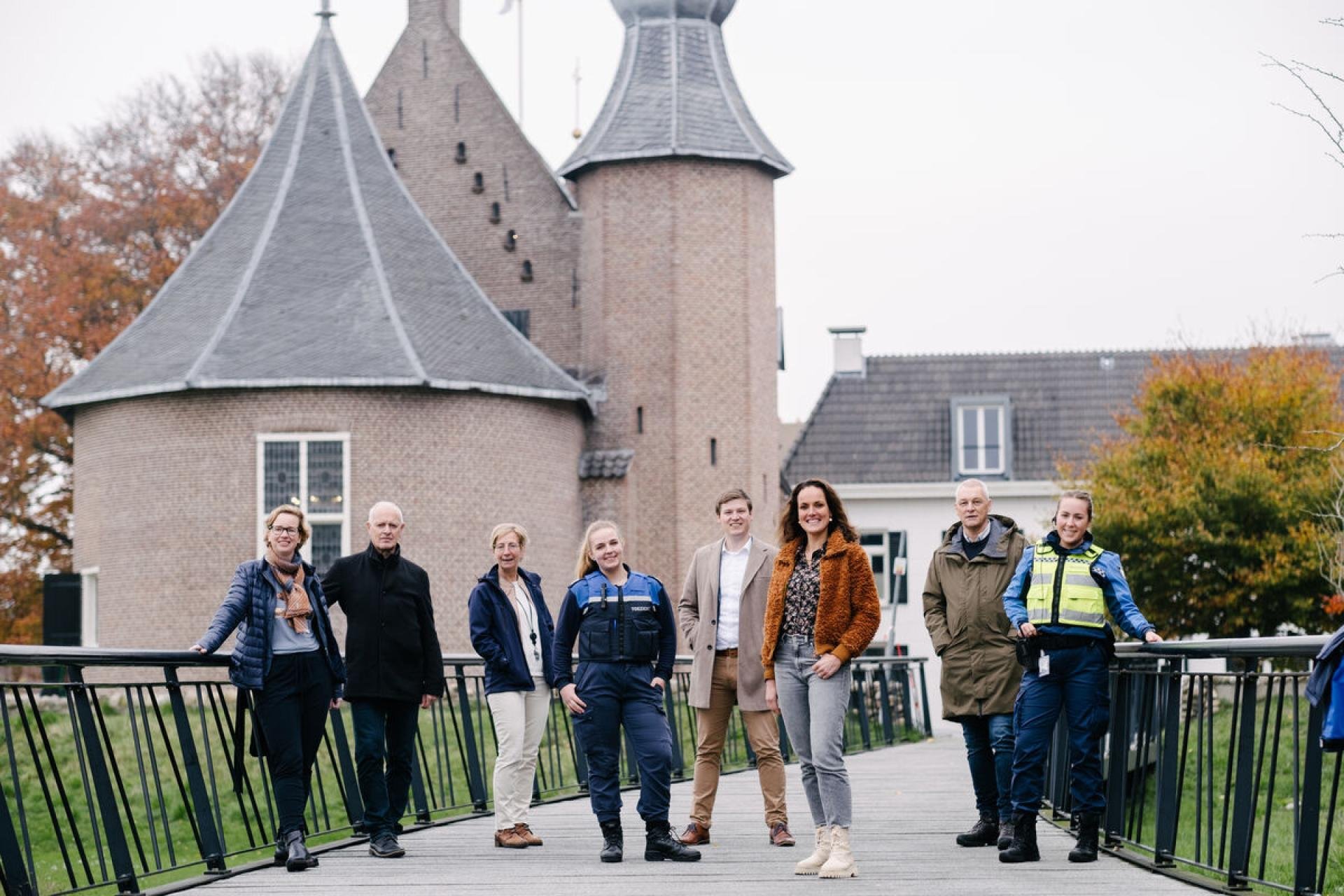 Acht medewerkers staan op de loopbrug in het kasteelpark van Coevorden. Op de achtergrond het kasteel van Coevorden.